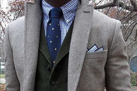 Here, the blue knit tie with spots is matched with a blue edged cotton print pocket square. The stripes play off the gingham checks giving the look added complexity.