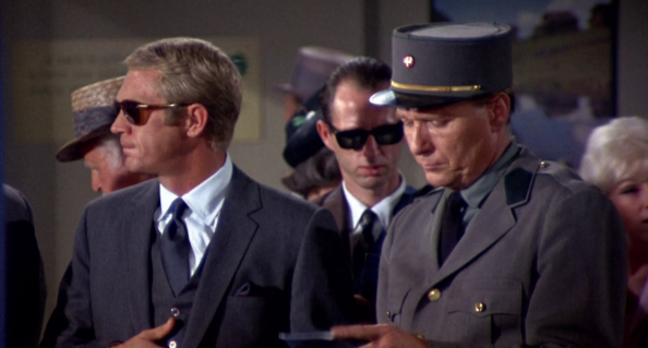 A man can never go wrong with a charcoal grey three-piece like the one worn by Thomas Crown as he waits to clear immigration.